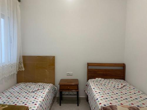 a bedroom with two beds and a table and a window at HALA Chaouni in Tétouan