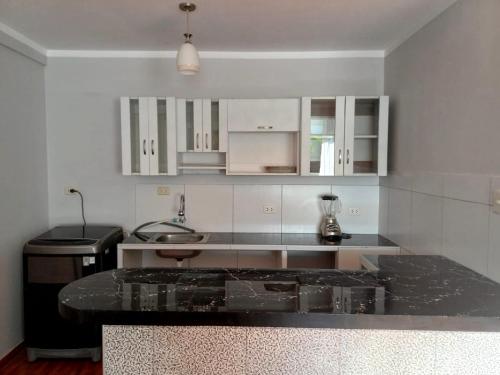 ハエンにあるModern and cozy apartmentの白いキャビネットと黒いカウンタートップを備えたキッチン