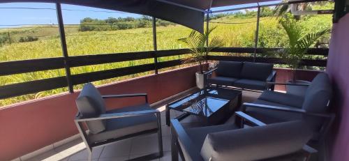 a room with chairs and a table and a field at Fleur de Canne in Saint-Pierre