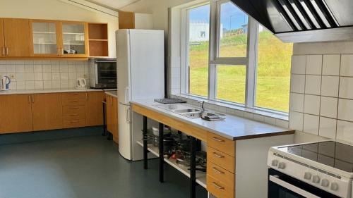 a kitchen with a white refrigerator and a sink at Helgafell Hostel in Djúpivogur