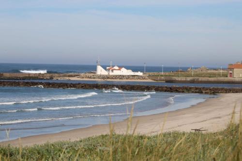 ein Strand mit einem Haus und das Meer mit Wellen in der Unterkunft Naval Beach Apartment in Azurara