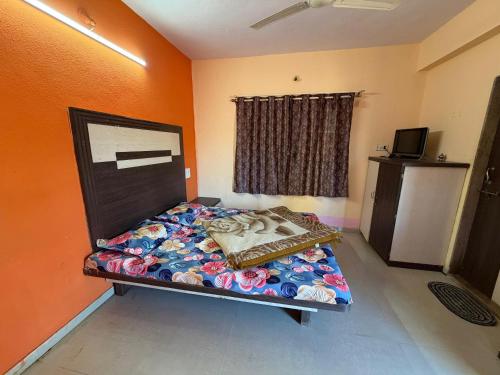 Ce lit se trouve dans un dortoir doté d'un mur orange. dans l'établissement Hotel Sudama Palace - Mahabaleshwar , Couple & Family Stay Rooms with Free Wi-Fi & Delicious Food, à Mahabaleshwar