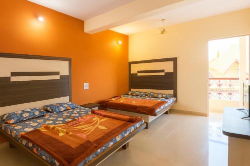 deux lits dans une chambre aux murs orange dans l'établissement Hotel Sudama Palace - Mahabaleshwar , Couple & Family Stay Rooms with Free Wi-Fi & Delicious Food, à Mahabaleshwar