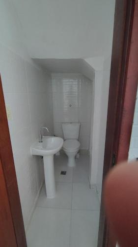 a white bathroom with a toilet and a sink at Casa na Guilhermina 500mt da praia in Praia Grande