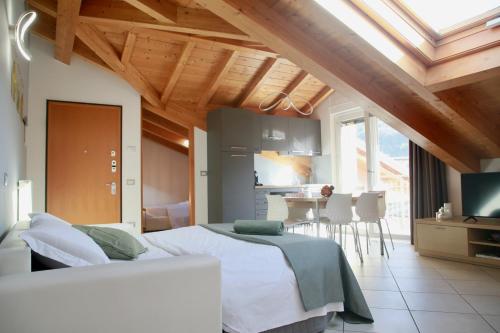 a bedroom with a white bed and a kitchen at La Fossola - vicino al Bernina Express in Tirano