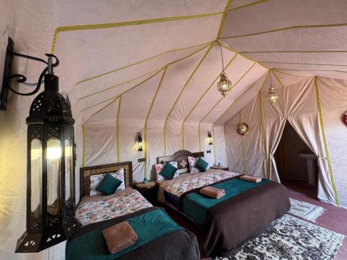 een slaapkamer met 2 bedden in een tent bij Merzouga Desert Campsite &Activities in Merzouga