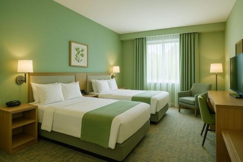 a hotel room with two beds and a television at GreenLeaf Serenity Hotel in Kalodran