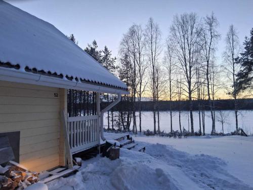 een met sneeuw bedekte hut met uitzicht op een meer bij Toivon pieni rantamökki in Sonka