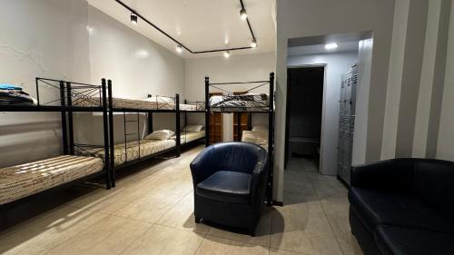 a room with three bunk beds and a chair at Sumaq Hostel Backpackers in Buenos Aires