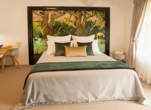 a bedroom with a large bed with a painting on the wall at Appart'Hotel Premium Le Roitelet - Parking Privé & Entrée Autonome in Tullins