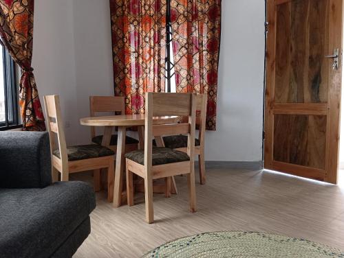 a room with a table and chairs and a couch at Nyumbani House in Mto wa Mbu