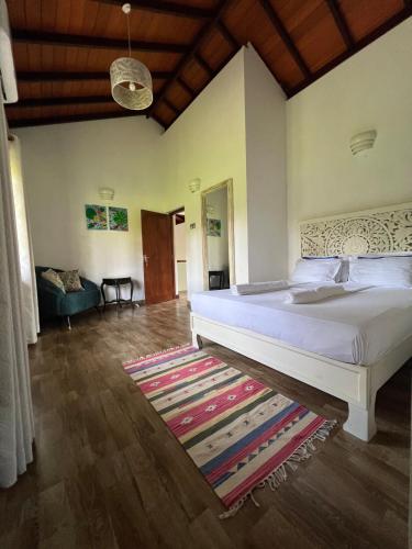 a bedroom with a large white bed and a rug at Forest Avenue - Kurunegala in Torayaya