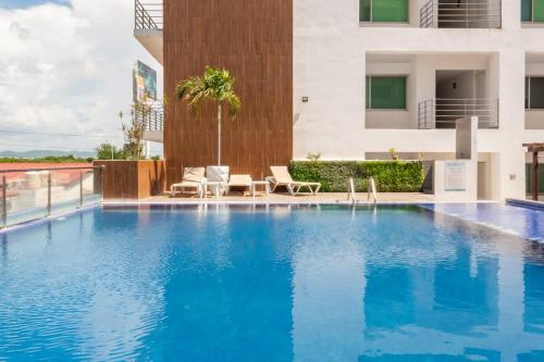 einem großen blauen Pool mit zwei Stühlen und einem Gebäude in der Unterkunft Amplio departamento con alberca in Los Cerritos