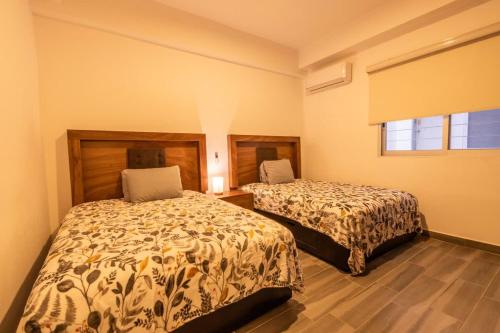 ein Schlafzimmer mit zwei Betten und einem Fenster in der Unterkunft Amplio departamento con alberca in Los Cerritos