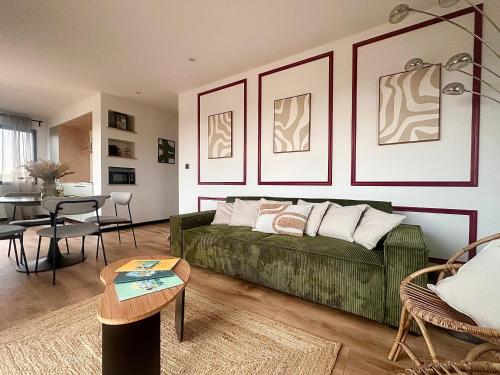 ein Wohnzimmer mit einer grünen Couch und einem Tisch in der Unterkunft Escale Doullennaise - Appartement neuf avec terrasse in Doullens