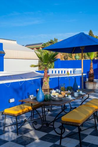 a table with chairs and an umbrella on a patio at Riad Goloboy in Marrakech