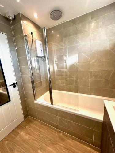 a bathroom with a shower and a tub at Druridge Apartment in Cowpen