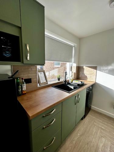 a kitchen with green cabinets and a sink at Druridge Apartment in Blythe
