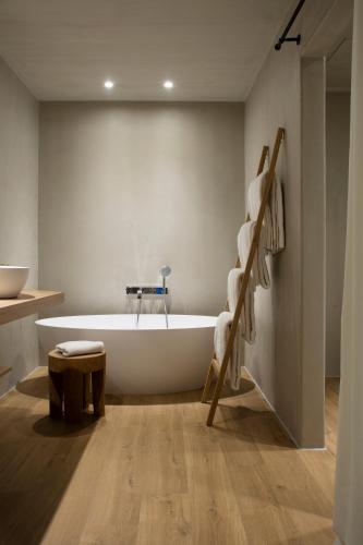 a bathroom with a white tub and a wooden floor at Hotel Peralada Wine Spa & Golf in Peralada