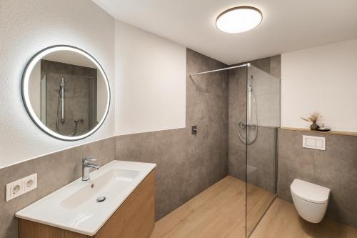 Un baño con lavabo, inodoro y espejo. en Seeapartment Angerer, en Terfens