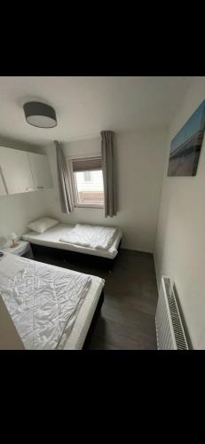 two beds in a small room with a window at Chalet Home Texel in De Koog