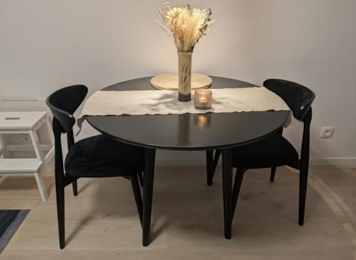 une table noire avec des chaises noires et un vase avec des fleurs dans l'établissement SADBA Apartment, 1-4 guests, Free Parking & Wifi, 15 min from Downtown, à Bratislava