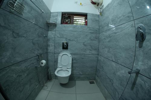 baño con aseo, ventana y teléfono en The Kayal Delight, en Cheruvattūr