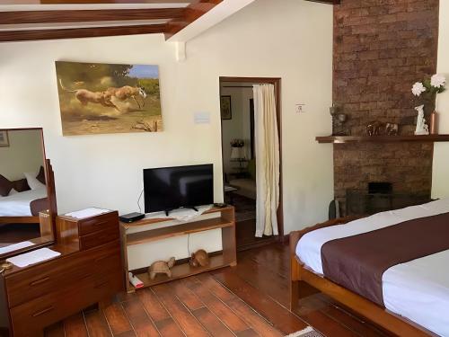 西隆Mid Hill Cottage Guest Suites Nongrim的一间卧室配有一张床和一张桌子上的电视