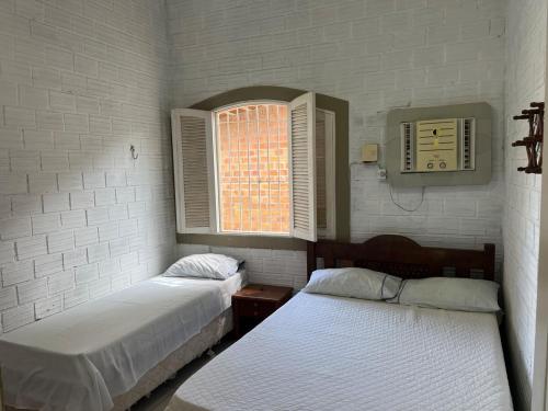 a bedroom with two beds and a window and a clock at Casa em Itamaracá - 70 metros da Praia in Itamaracá