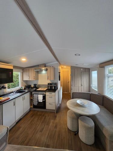 a kitchen and living room with a table and a couch at 'By The Stream' 60 The Beeches in Prenteg