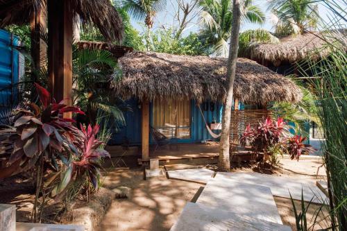 a small house with a straw hut with palm trees at NOMA San Agustinillo in San Agustinillo