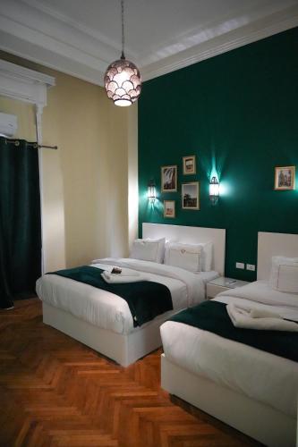 due letti in una camera da letto con una parete verde di Hathor House a Il Cairo