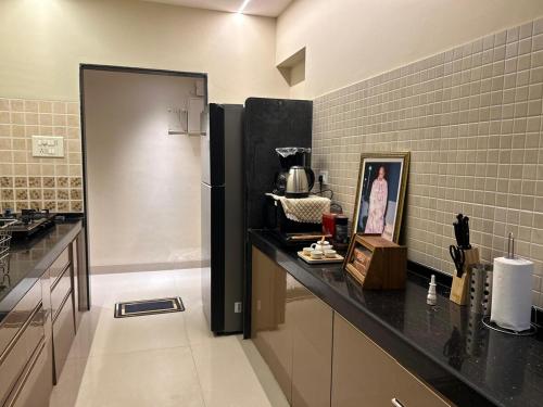 Una cocina con encimera negra y refrigerador. en Luxury Aesthetic Party Pad, en Bombay