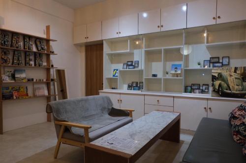 a living room with a chair and a table and shelves at Films House Hostel in Bangsaen