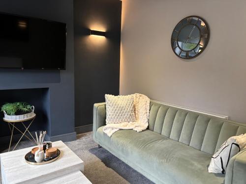 a living room with a green couch and a tv at Cottage in Holmfirth Centre in Holmfirth