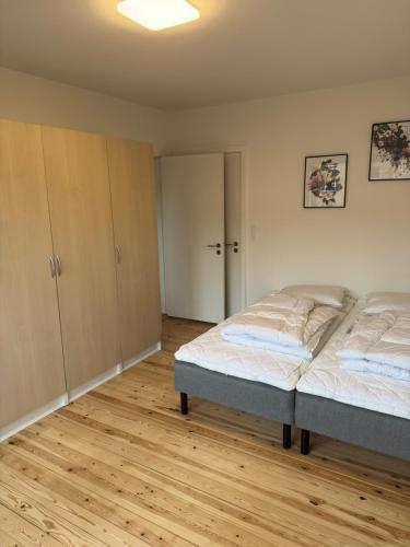 a bedroom with two beds and a wooden floor at Flot 3 værelses lejlighed - op til 6 personer in Randers