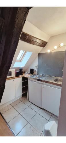 a kitchen with white cabinets and a window at L'Envolée Mansardée - Center in Chartres
