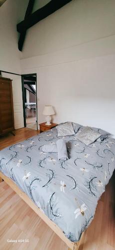 a bed with a blue comforter with flowers on it at L'Envolée Mansardée - Center in Chartres