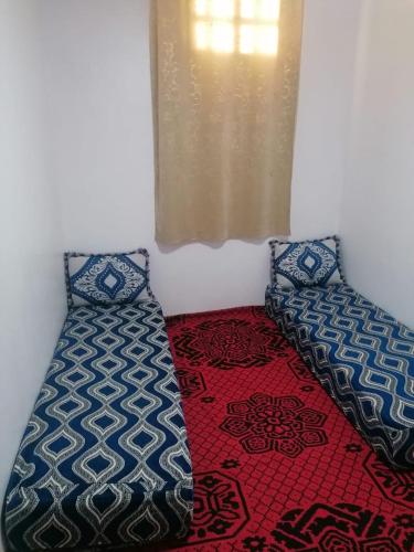 a room with a bed and pillows and a window at شقة مريحة بجانب مطار المسيرة اكادير in Ikhorbane