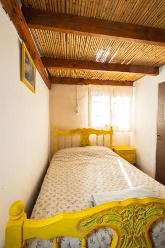 a yellow bed in a bedroom with a wooden ceiling at Cabañas rainbow in San Marcos Sierras
