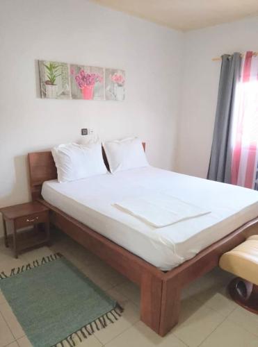 a bedroom with a large bed with white sheets at Residence Merveilles CM15 in Kribi