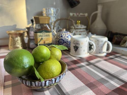 a bowl of limes sitting on a table with cups at A house in the woods in Patara Etseri