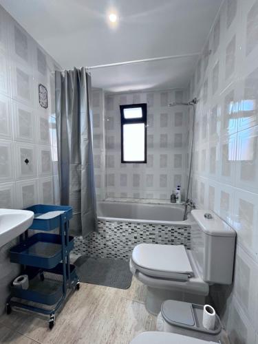 Casa Blanca - apartamento en Gandia في غانديا: حمام مع مرحاض ومغسلة وحوض استحمام