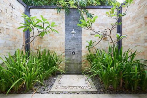 un jardín con una fuente en una pared de ladrillo en Octopus Villas, en Tejakula