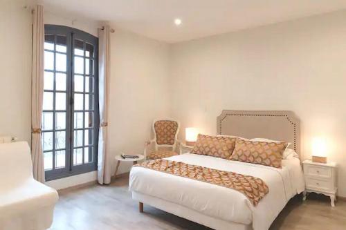 a white bedroom with a bed and a chair at Studios MISTRAL21 en Camargue in Salin-de-Giraud