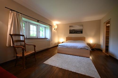 a bedroom with a bed and a chair and windows at Le Nid d'à côté in Méan