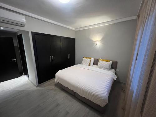 塔哈佐特Luxury 2BR Apartment Taghazout Bay 1 min walk to beach的卧室配有白色的床和黑色橱柜。