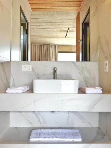 a white bathroom with a sink and a mirror at Flat Camburi in Camburi