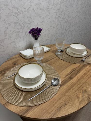 einen Tisch mit Tellern und Gläsern und eine Vase mit Blumen in der Unterkunft Однокомнатная квартира 463 in Qostanai