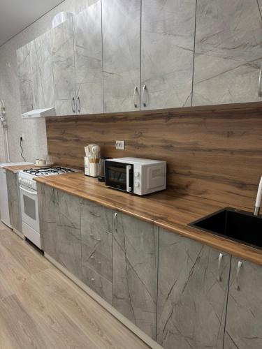 eine Küche mit einer Mikrowelle auf einer Holztheke in der Unterkunft Однокомнатная квартира 463 in Qostanai